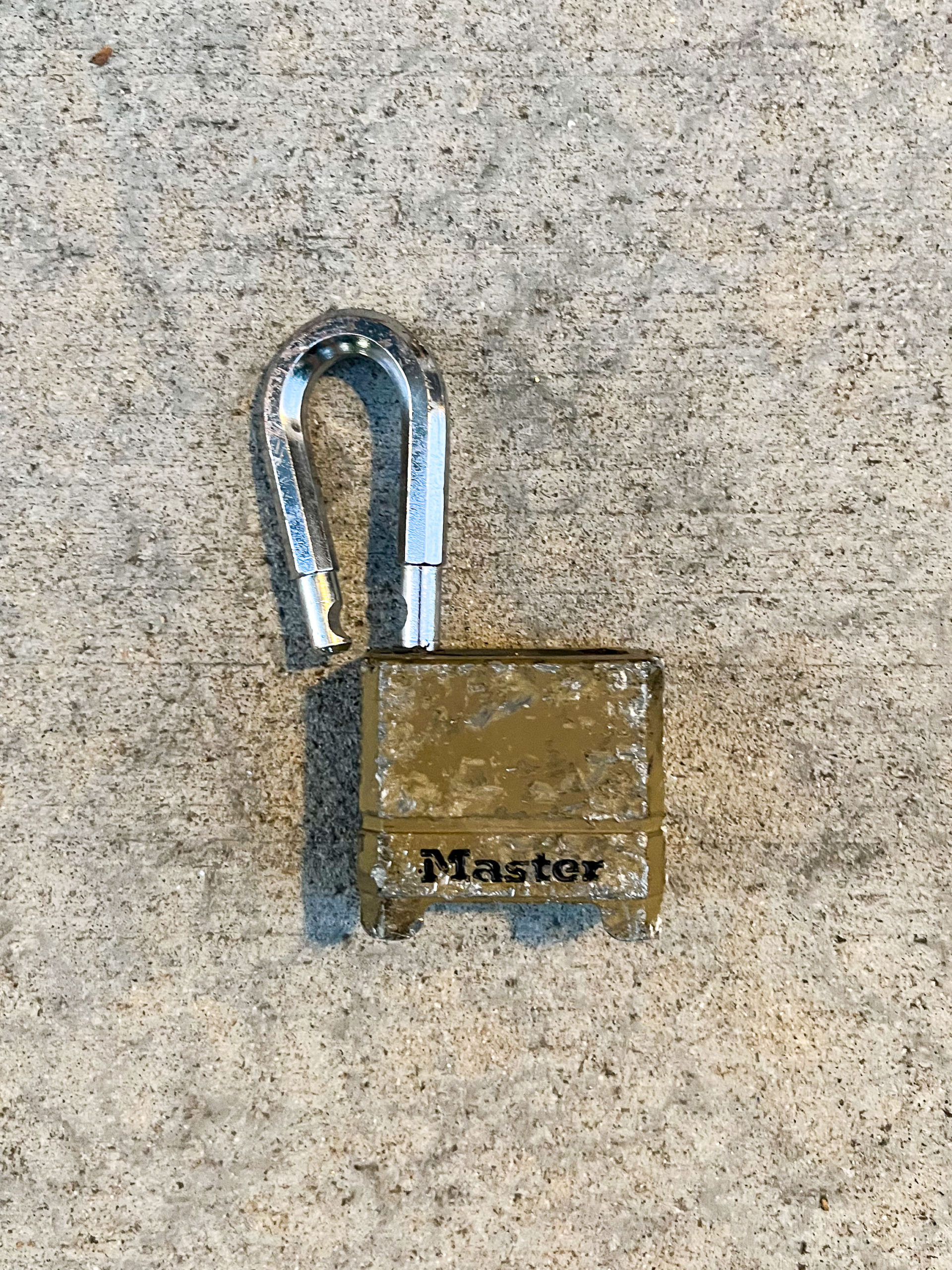 Scratched brass Master lock with a bent shackle in unlocked position