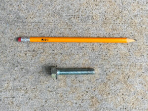 Barely-used number 2 pencil and 2-inch hex bolt