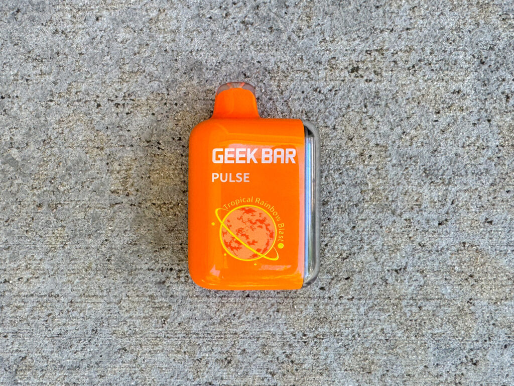 Bright orange, used Geek Bar Pulse vape device in "Tropical Rainbow Blast" flavor.