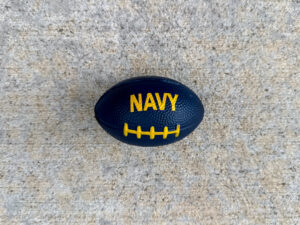 Dark navy blue football-shaped stress ball with yellow "NAVY" text and yellow laces