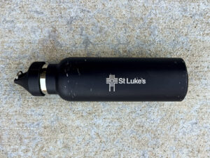 Black metal TOPL water bottle with silver "St Luke's" logo, showing light wear and scratches