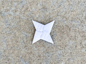 Folded paper ninja star made from lined notebook paper.