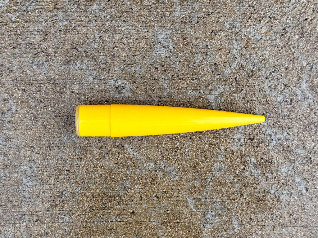 A bright yellow plastic model rocket nose cone with a tapered shape.