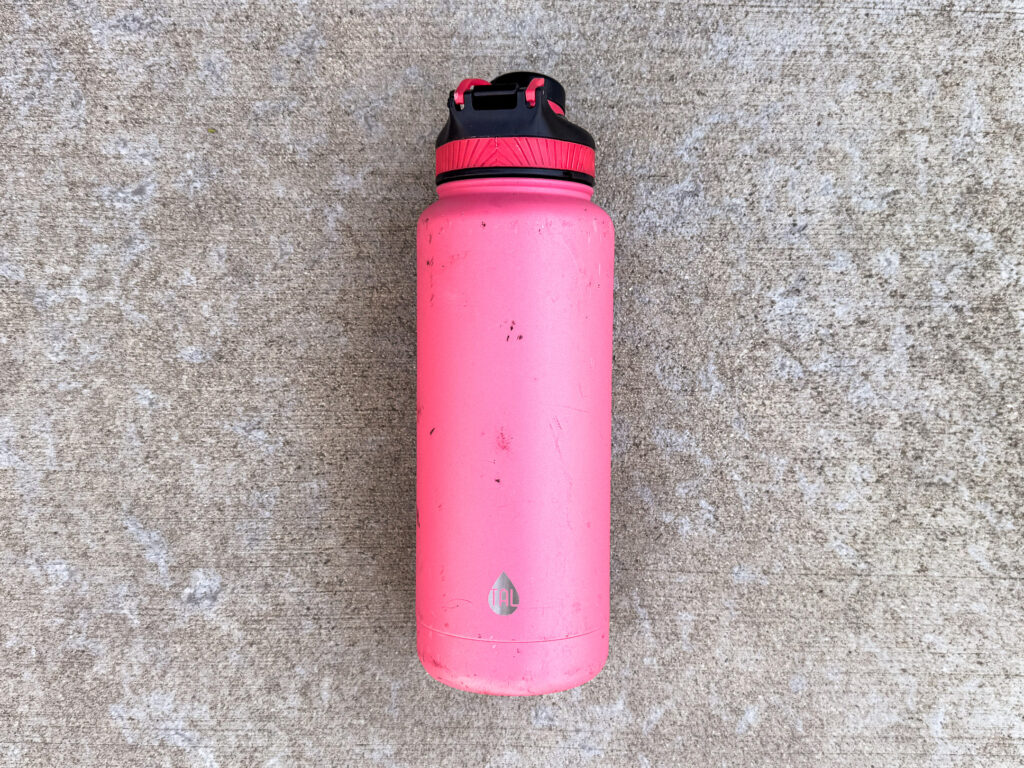 A scuffed pink 40oz. TAL Ranger Pro water bottle with a black and pink lid.