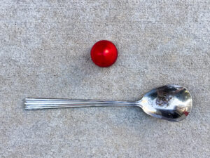 A 2-inch red beehive trailer light positioned above a large silver serving spoon with a pitted bowl.