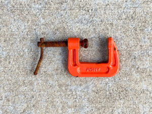 Small orange PONY brand C-clamp with a heavily rusted spindle and handle.