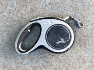 Flexi brand retractable dog leash with a black and silver casing, showing a leaping dog graphic and the words “Made in Germany.”