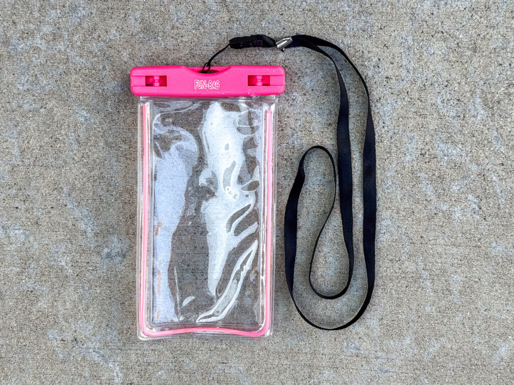 A clear waterproof phone pouch with a hot pink seal labeled “FUN-BAG”, attached to a black lanyard.