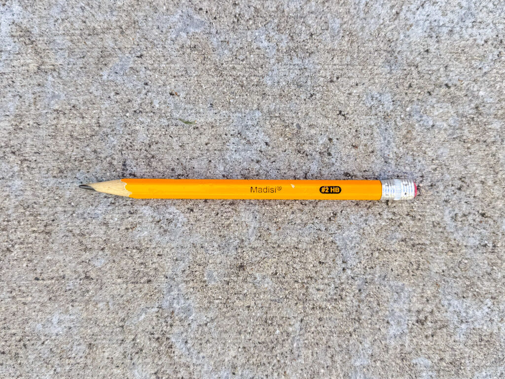 A yellow Madisi #2 HB pencil, about one-third used, with a worn eraser and sharpened tip.