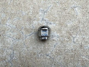 A shiny chrome acorn lug nut with “12x1.5” engraved on one of the flats.