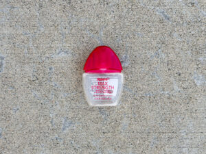 Nearly empty small clear bottle of Rohto Max Strength eye drops with a red cap.