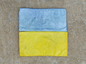 Two microfiber cloths arranged like the Ukraine flag—light blue on top, yellow on bottom—laid flat with visible wear and smudges.