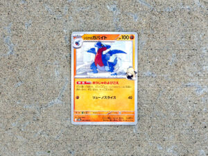 Japanese Pokémon card featuring Garchomp with 100 HP, showing a blue dragon-like character in the artwork, lying flat.