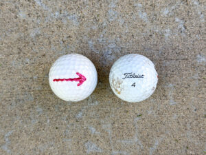 Two white golf balls side by side; the left has a red arrow pointing right, and the right is a Titleist 4 with light dirt marks.