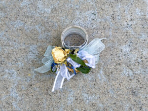 Dried wrist corsage with flowers, greenery, ribbon, and a silver ribbed cuff.