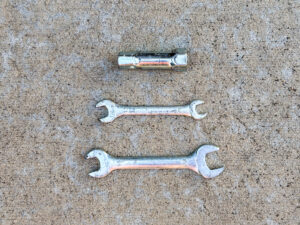 A scuffed chrome box spanner above two double open-end wrenches: one 10×12mm, the other 14×17mm.